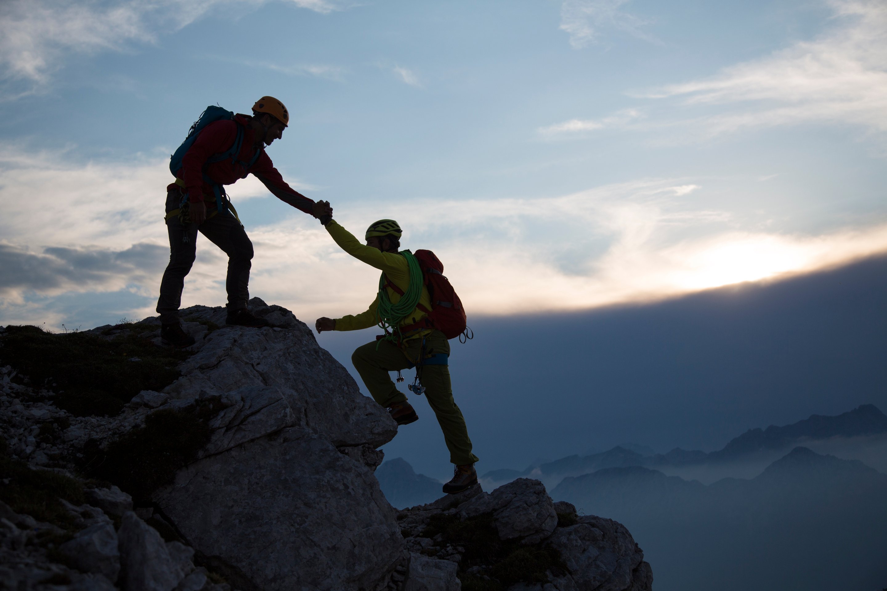 Man helping friend to climb rock mountain